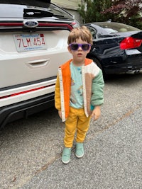 a young boy wearing sunglasses in front of a car